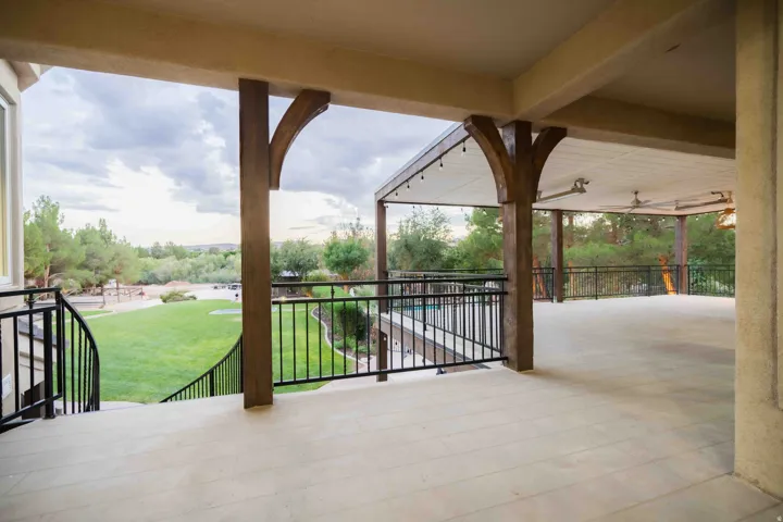 Expansive covered patio featuring a concrete floor, dark wood-finish support beams, and recessed ceiling fans