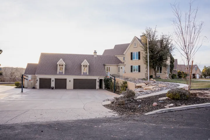 Stucco exterior with a multi-car garage, dormer windows, and a concrete driveway