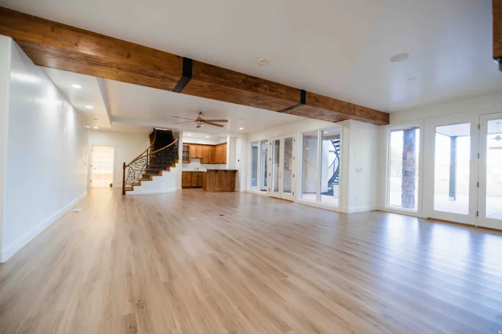 Spacious interior with wood-finish flooring, exposed wood beams, recessed lighting, and multiple glass-paned doors