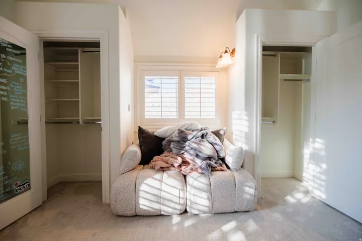 Carpeted flooring with built-in closets featuring shelving and hanging rods
