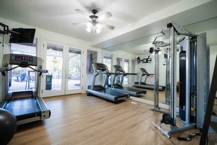 Wood-finish flooring with full-wall mirrors and a ceiling fan