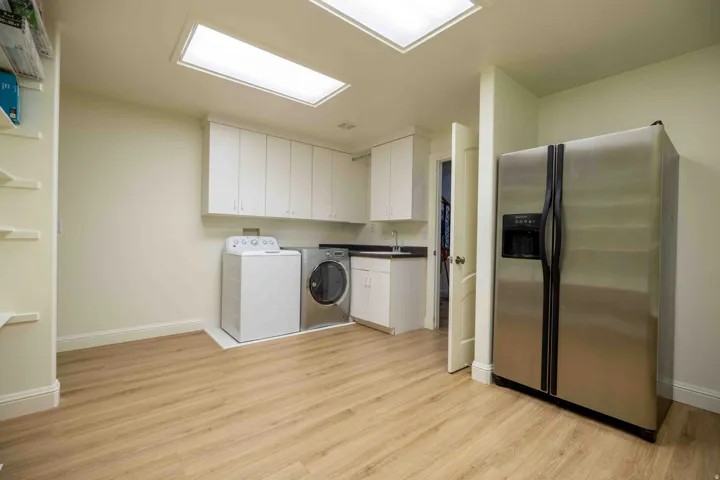 Recessed lighting and skylights illuminate this room with wood-finish flooring