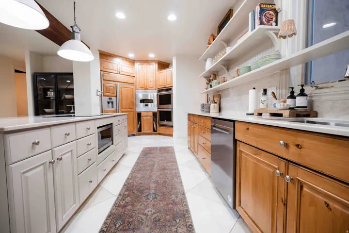 Kitchen featuring white tile flooring, light wood cabinetry, white countertops, stainless steel appliances, and open shelving