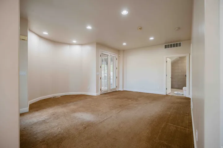 basement casita Recessed lighting, curved wall, white French doors, brown carpet flooring, and an open doorway