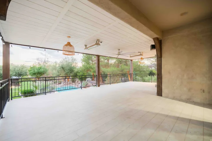 Expansive covered patio with planked ceiling, integrated ceiling fans, and tiled flooring