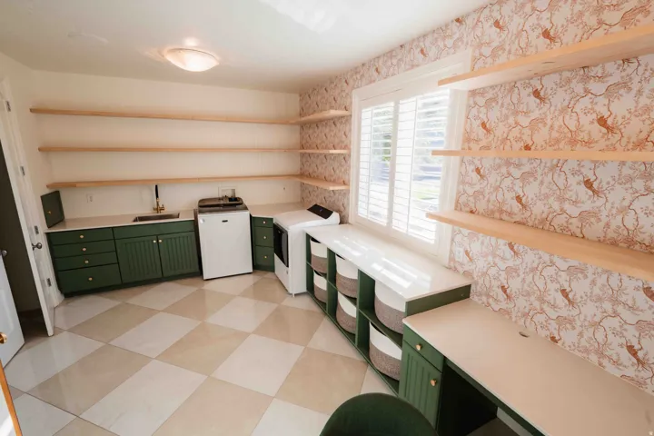 Spacious utility room featuring checkerboard tile flooring, green cabinetry, white countertops, and extensive built-in shelving