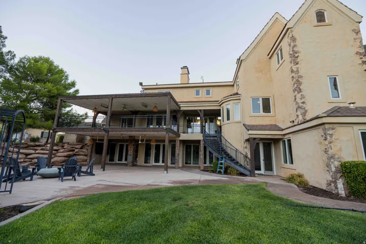Expansive exterior featuring a stucco finish with stone accents, multiple large windows, and a multi-level covered patio