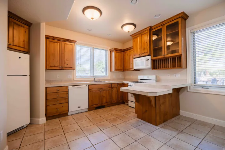 basement casita Kitchen featuring wood cabinetry, tiled countertops, integrated appliances, and a tiled floor