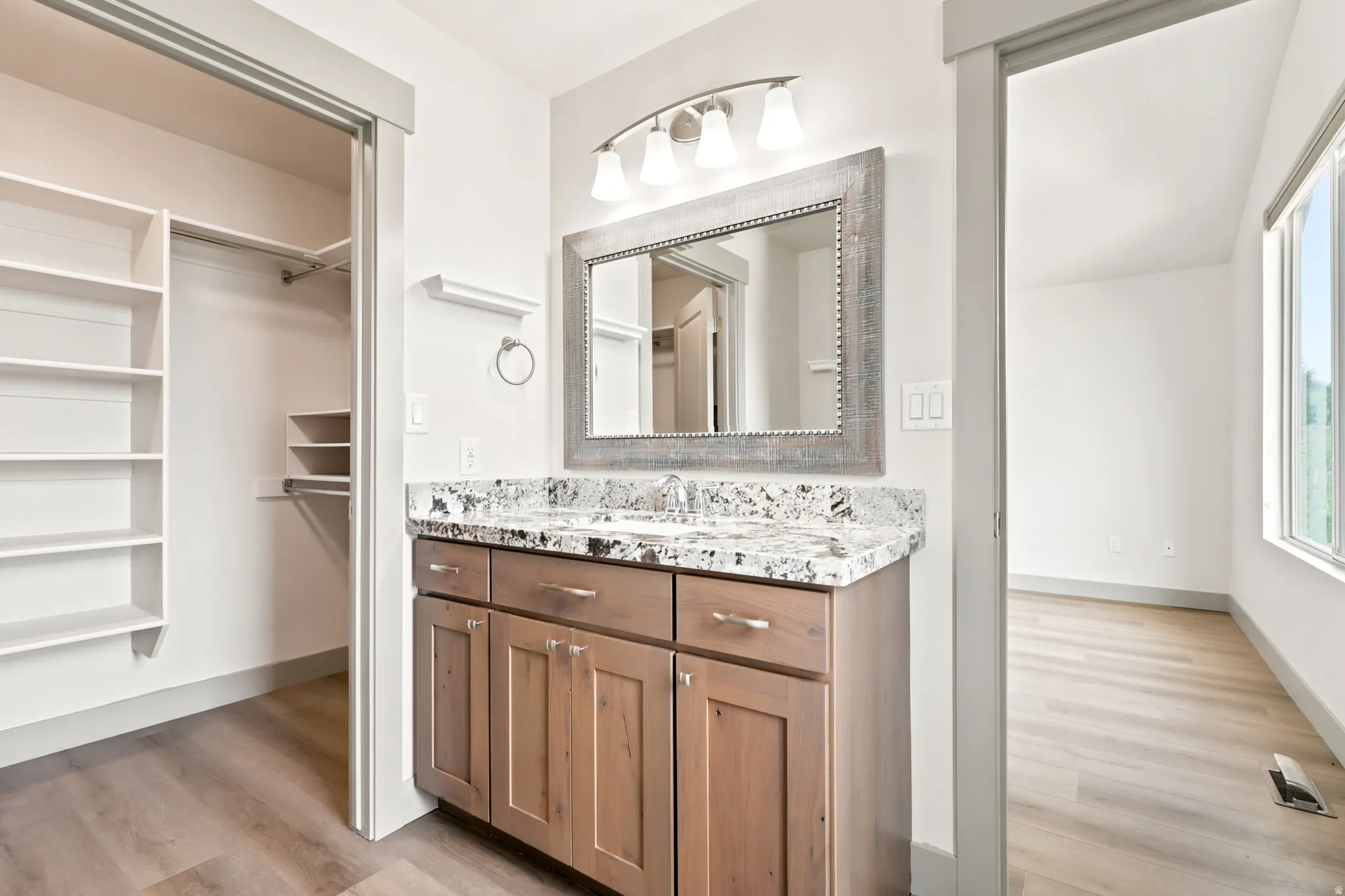 Vanity with a granite-style countertop, undermount sink, and wood-finish cabinetry