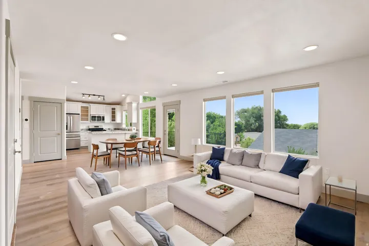 Open-concept living area featuring wood-finish flooring, recessed lighting, and multiple large windows