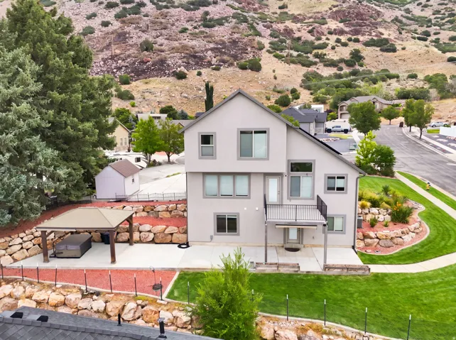 Contemporary-style home featuring a rear balcony, ground-level patio, and a covered outdoor structure