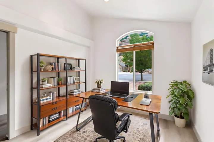 Arched window with wood-finish blinds, light wood-finish flooring, and a built-in shelving unit with drawers