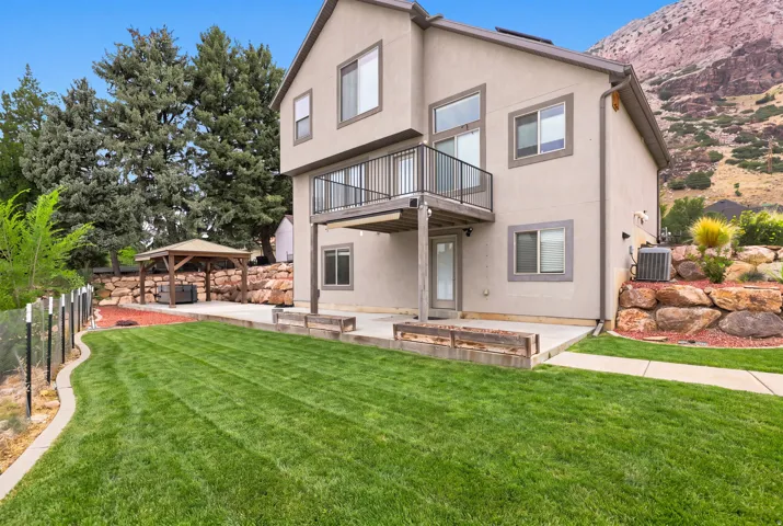 Expansive rear yard featuring a concrete patio, wood-finish raised garden beds, and a covered gazebo structure
