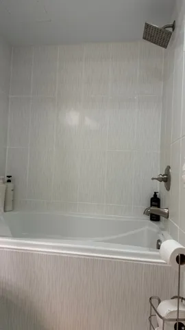 Bathtub with integrated shower, tiled surround, and brushed nickel fixtures