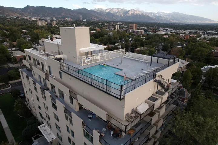Rooftop swimming pool with surrounding deck, integrated pergola, and exterior stairs