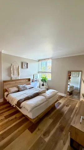 Wood-finish flooring, crown molding, and a large window with privacy blinds