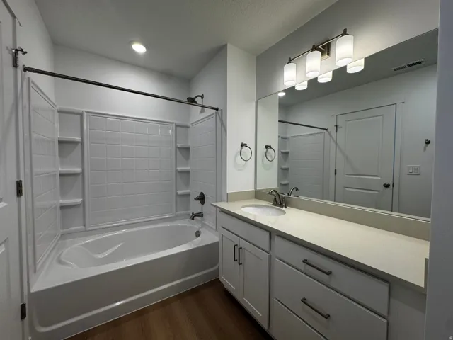 Bathroom with a large vanity featuring a light-colored countertop and integrated sink, cabinet storage, and a wide mirror
