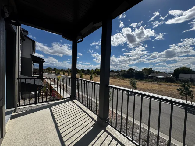 Covered balcony featuring concrete flooring and black metal railings