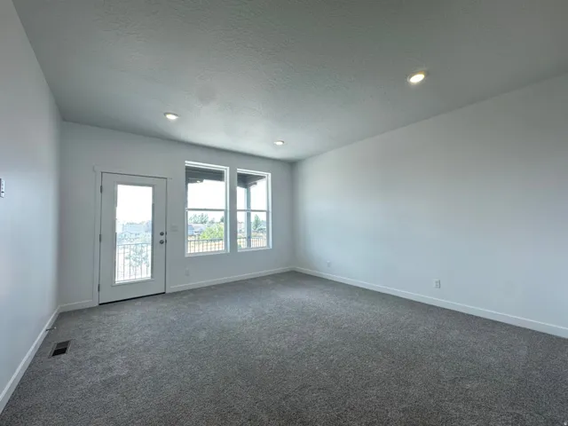 Recessed lighting, light gray carpeting, crisp white walls, and bright white trim