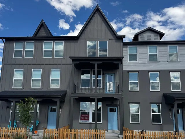 Contemporary townhome exterior featuring multi-toned siding, a prominent gabled roofline, and multiple paneled windows