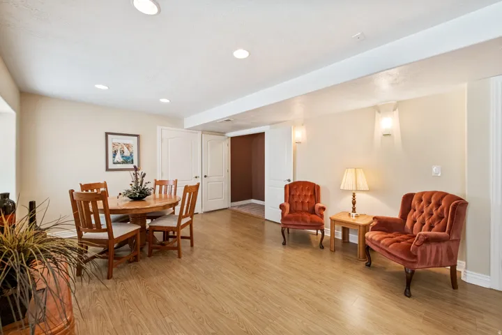 Wood-finish flooring, recessed ceiling lighting, and wall sconces illuminate the open space.