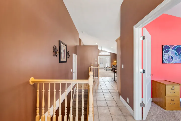 Tiled flooring throughout the hallway leads to an open living area with vaulted ceilings.