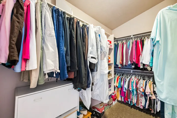 Oversized closet with multiple hanging rods & shelving units.