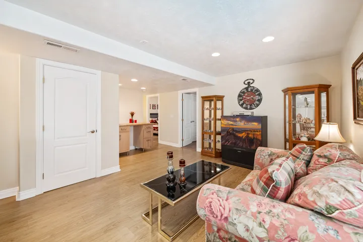 Recessed lighting illuminates the wood-finish flooring and light-toned walls