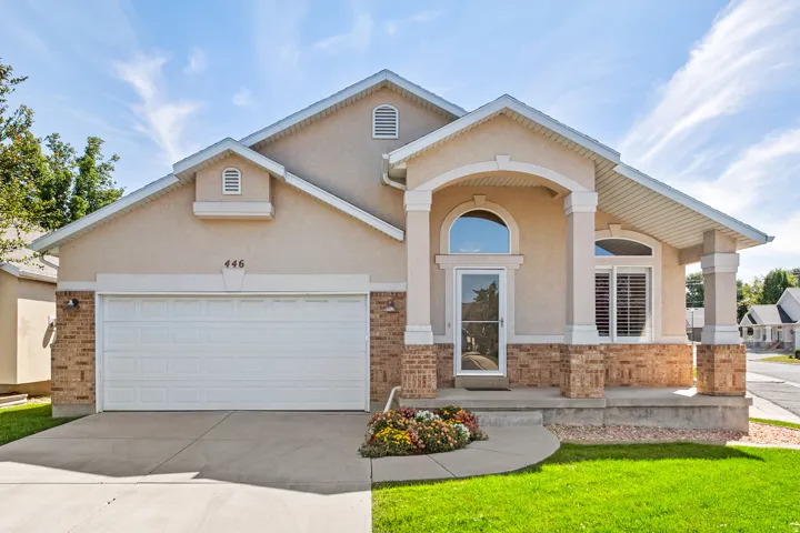 Stucco and brick exterior with a covered front porch, arched windows, and attached two car garage.