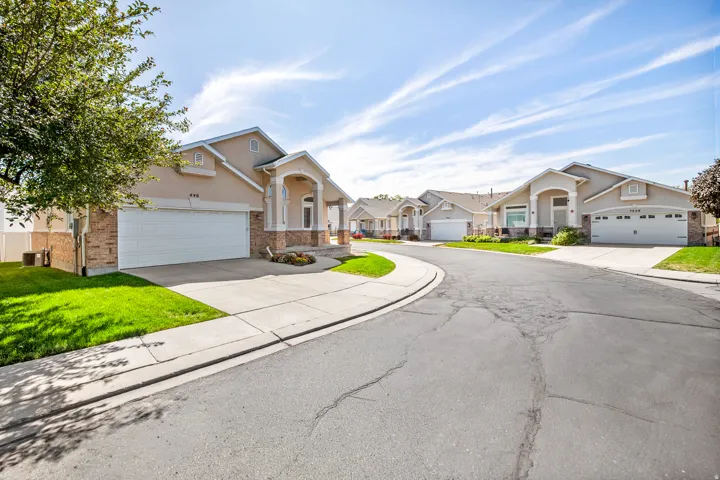 Stucco and brick facade with arched entry, attached garage, concrete driveway, and manicured landscaping.