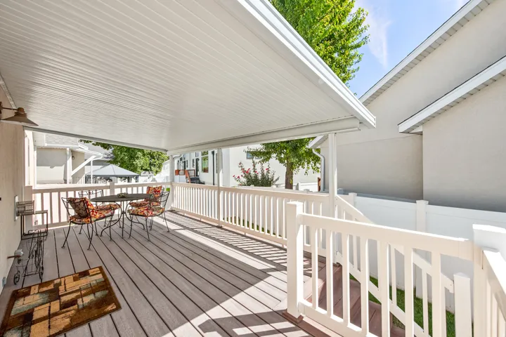 Large covered deck with TREX decking, white railing, and stairs to backyard.
