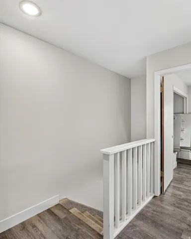 Recessed ceiling lighting, wood-finish flooring, white painted walls, and a white stair railing