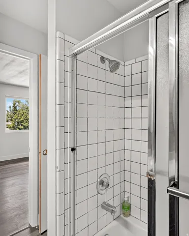 Shower enclosure with white square tile surround and polished chrome fixtures