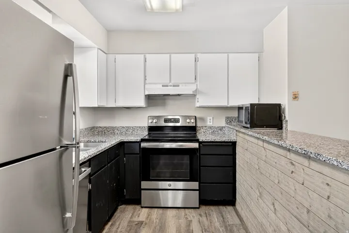 Kitchen featuring wood-finish flooring, granite countertops, and stainless steel appliances