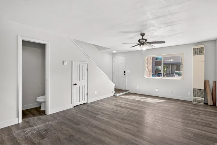 Wood-finish flooring throughout, ceiling fan with integrated lighting, and a prominent window