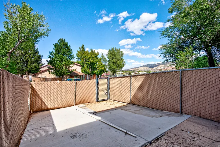 Chain link fencing with privacy slats, concrete patio area, and a fenced gate