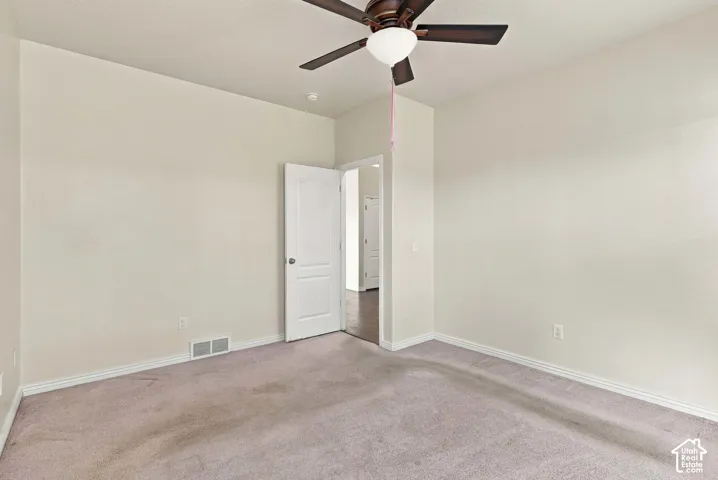 Neutral wall tones, ceiling fan with integrated lighting, white trim details, and wall-to-wall carpeting