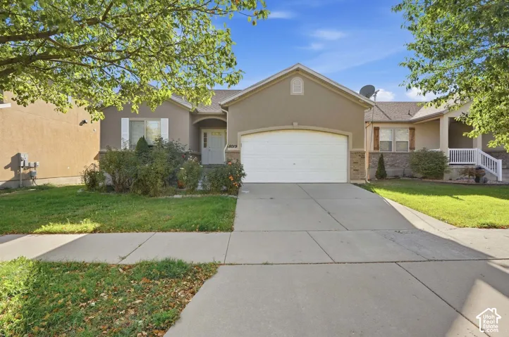 Exterior featuring a two-car garage, concrete driveway, and front landscaping