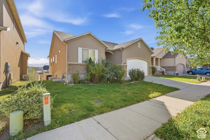 Stucco exterior with brick detailing, attached garage, and a concrete driveway