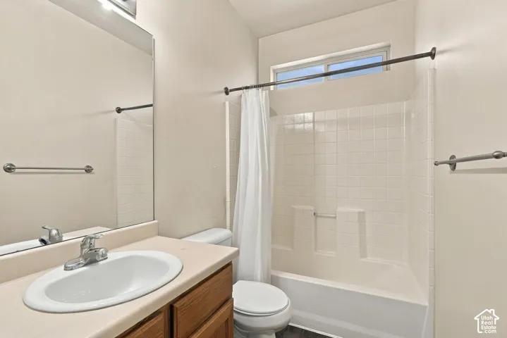 Vanity with wood-finish cabinetry and an oval sink, chrome faucet, and expansive mirror