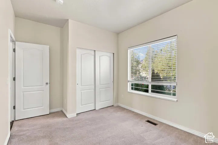 Neutral tone wall paint, light gray carpet, white trim, sliding closet doors, and window with blinds
