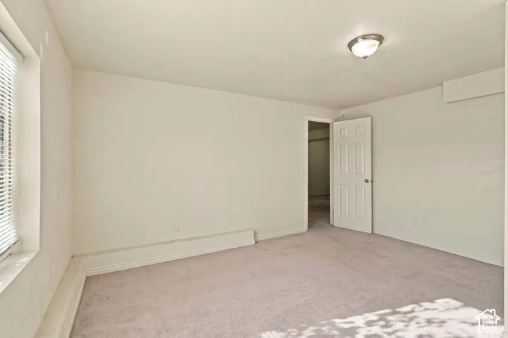 Recessed window with blinds, paneled door, flush-mount ceiling light fixture, and carpeted flooring