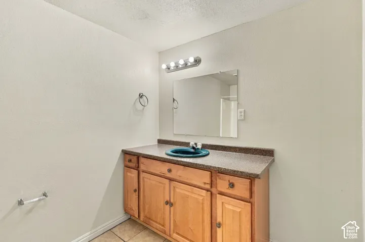 Wood-finish vanity with ample storage, a dark countertop, and an integrated basin