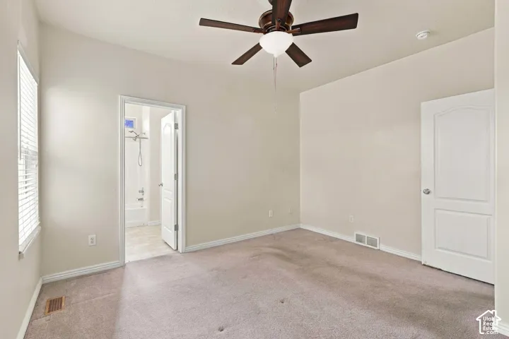 Vaulted ceiling, ceiling fan, carpet flooring, window with blinds, panel door