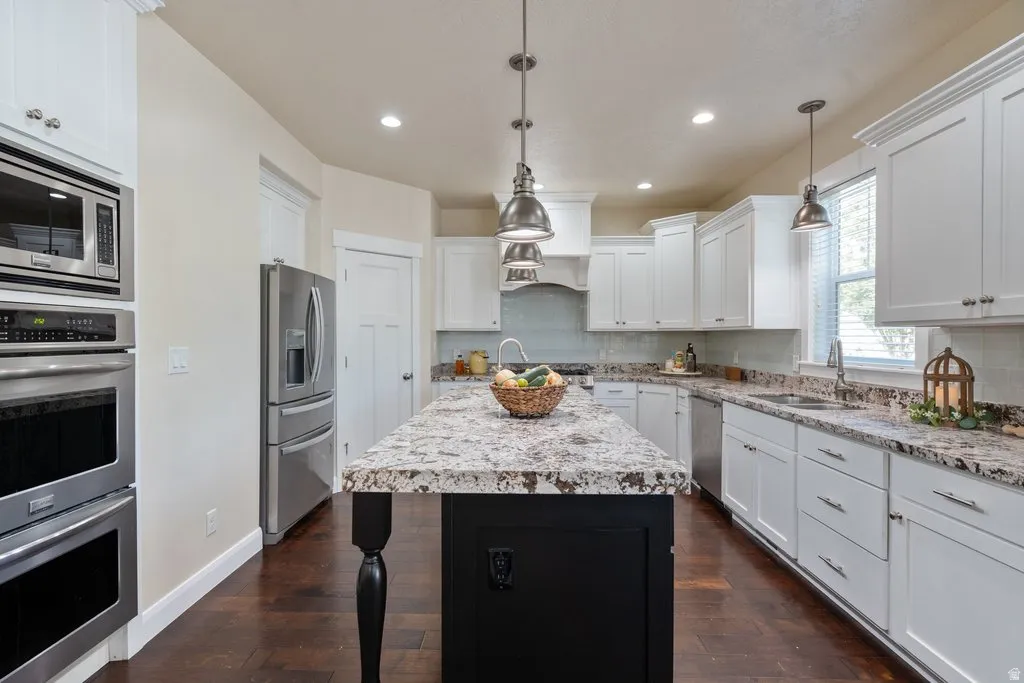 Kitchen featuring stainless steel appliances, white cabinetry, a large kitchen island with a contrasting base, wood-finish flooring, and pendant lighting