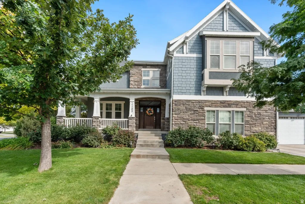 Stone and shingle exterior with a covered front porch featuring white columns and railing