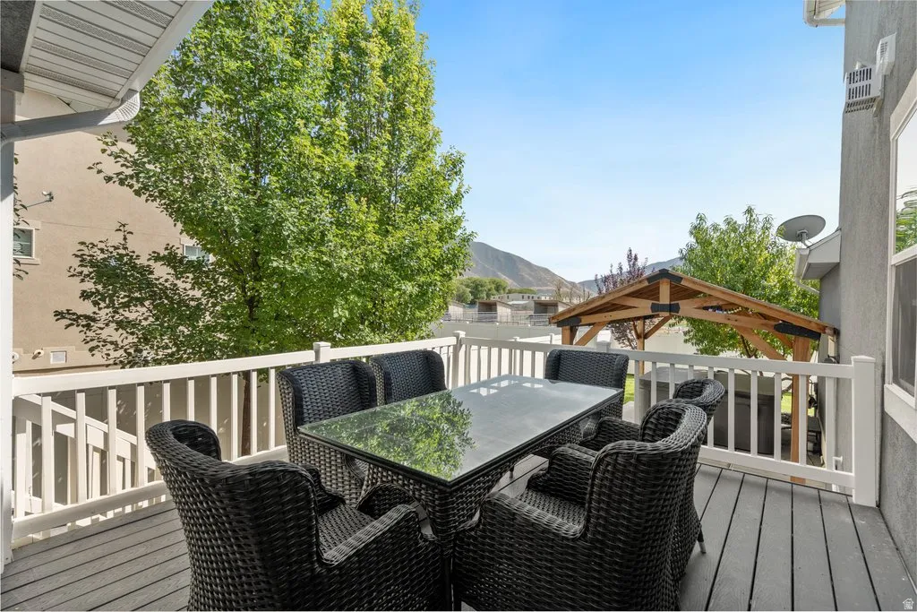 Elevated composite deck with white railings and black woven outdoor seating surrounding a rectangular dining table