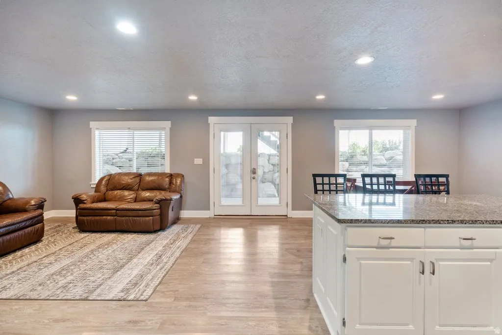 Spacious interior featuring wood-finish flooring, recessed lighting, and a kitchen island with stone-finish countertops and white cabinetry
