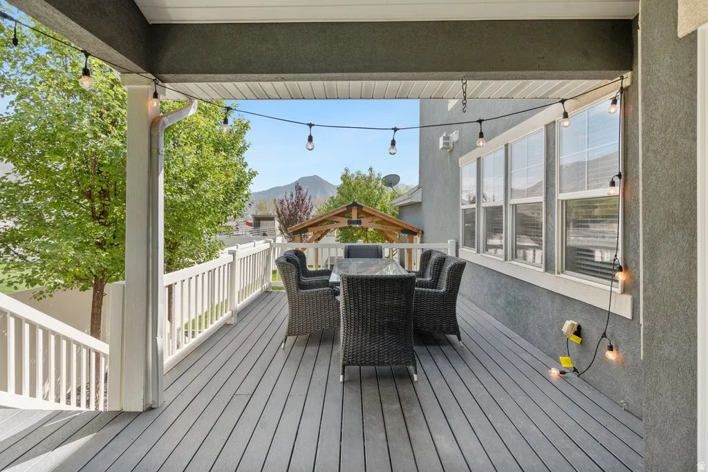 Expansive deck featuring gray composite decking, white railing, and an overhead string light installation