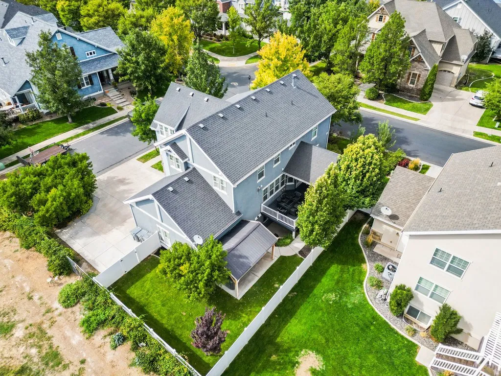 Property featuring a multi-level exterior, an attached rear deck, an expansive backyard with a manicured lawn, a covered patio, and mature landscaping